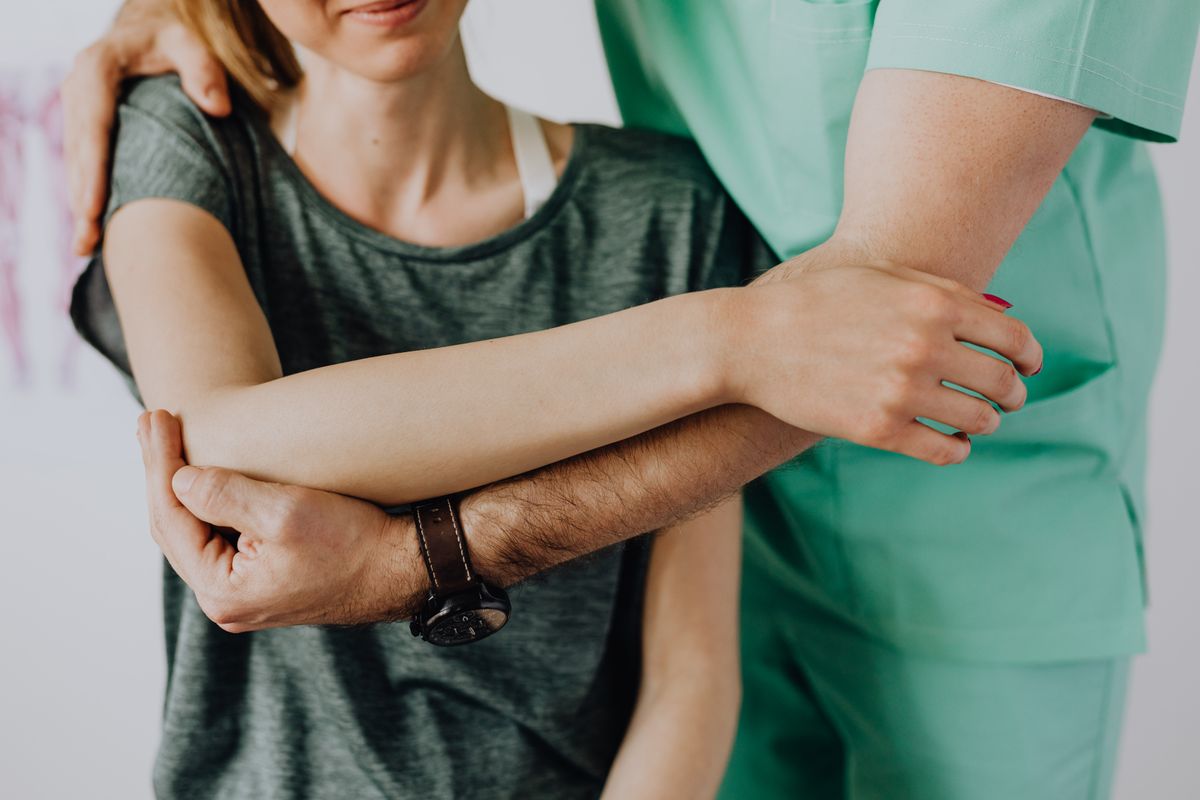 Behandler massiert die Hand eines Patienten als Teil einer chiropraktischen Behandlung