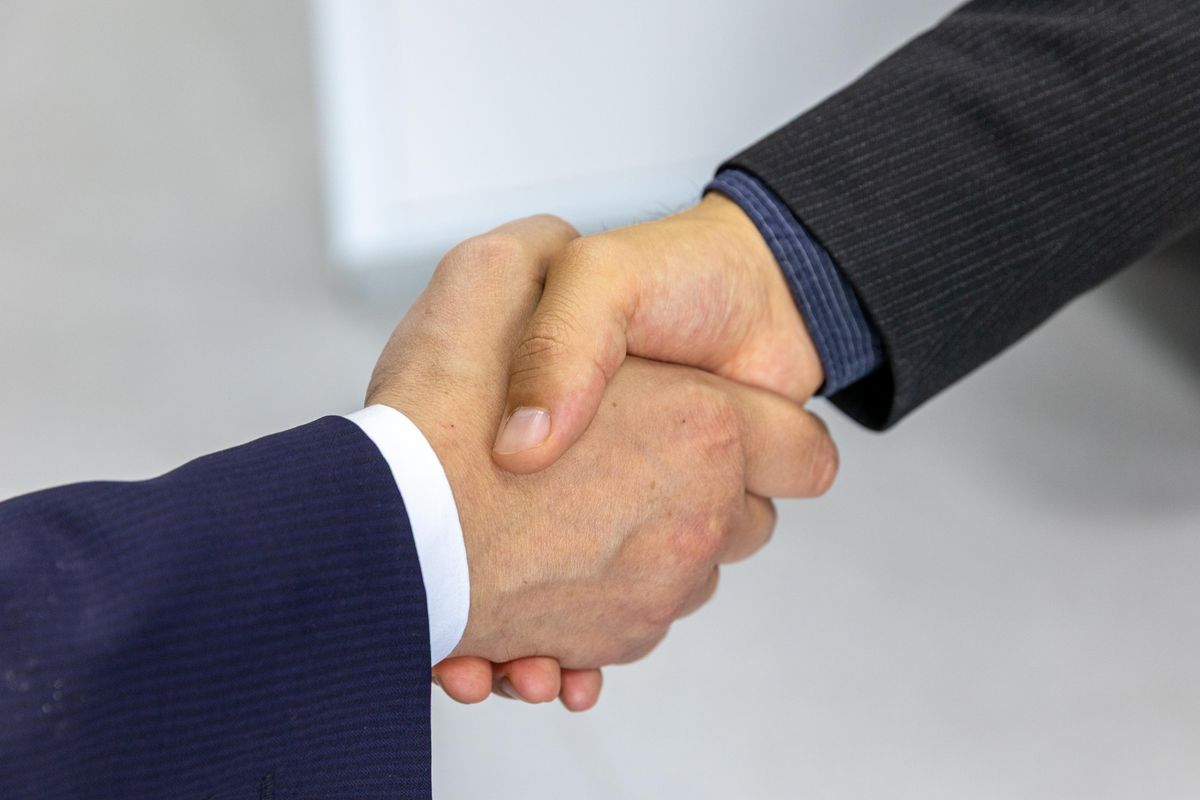Geschäftspartner besiegeln den Abschluss einer Gewerbeversicherung mit einem Handschlag