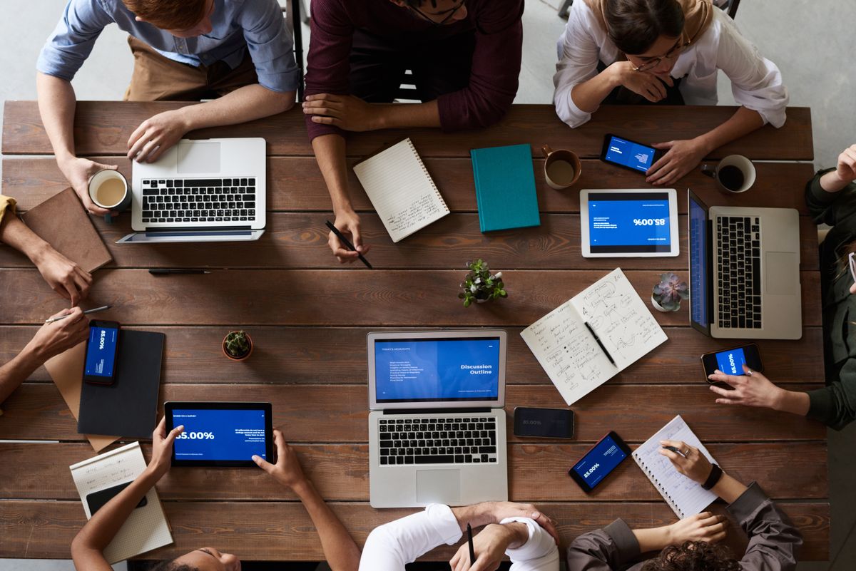 Beraterteam bespricht Kennzahlen und Umsatzentwicklung anhand von Laptops und Notizen