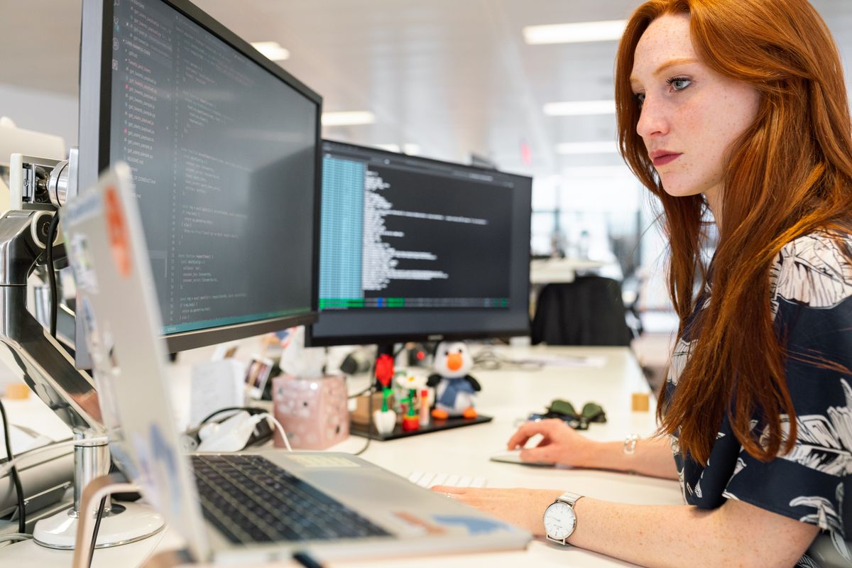 IT-Beraterin analysiert Daten und Quellcode an mehreren Bildschirmen im Büro