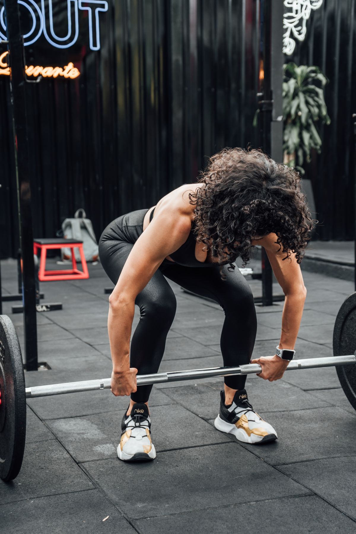 Sportlerin absolviert Krafttraining mit Langhantel in einem Fitnessstudio