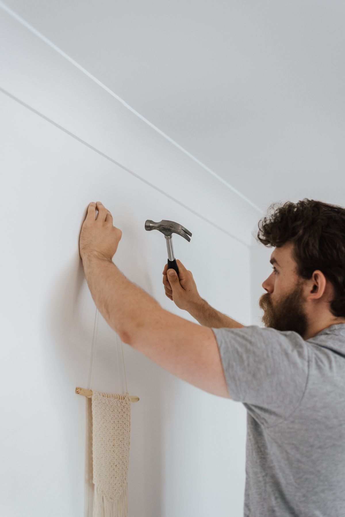 Handwerker schlägt einen Nagel in eine Wand während Renovierungsarbeiten