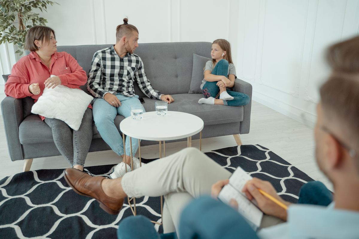 Familie im Beratungsgespräch mit einer Therapeutin auf dem Sofa in der Praxis
