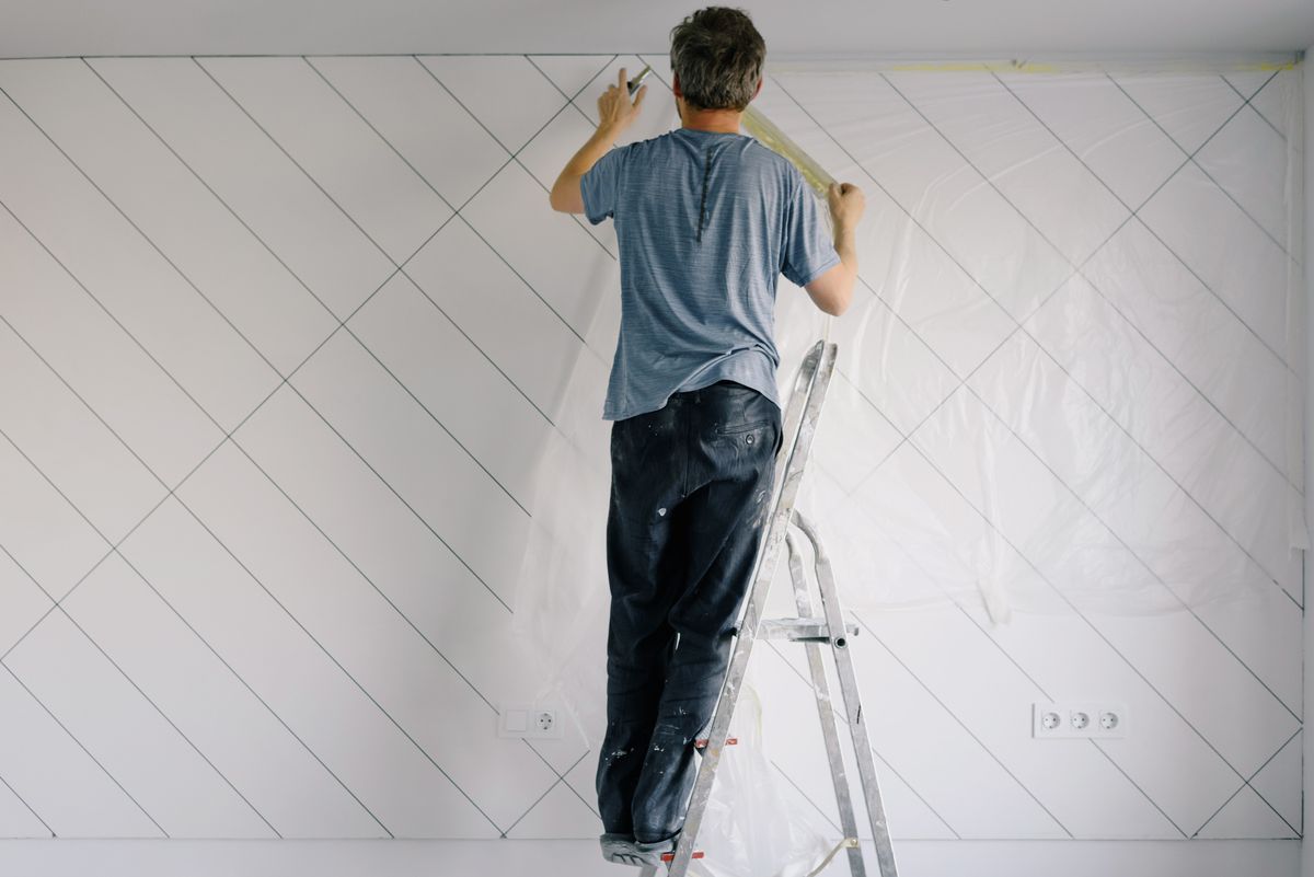 Maler grundiert eine helle Wand mit Farbroller in einem renovierten Raum