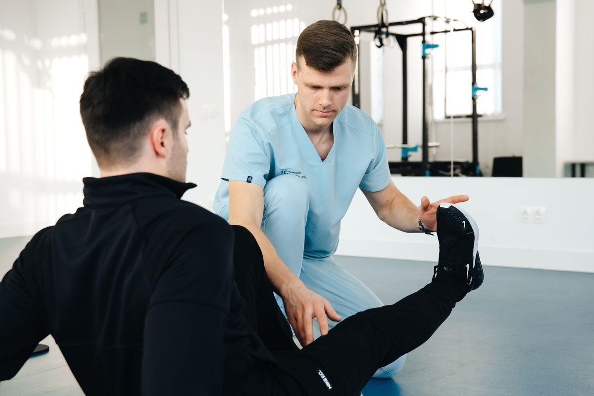 Physiotherapeut untersucht das Bein eines Patienten während einer Behandlung