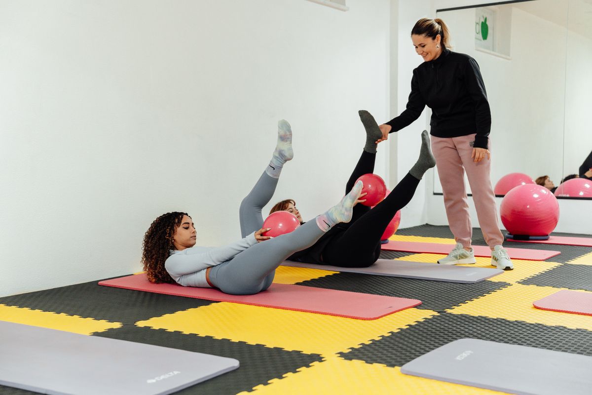 Gruppe von Frauen dehnt sich gemeinsam während einer Pilates-Stunde im Fitnessstudio