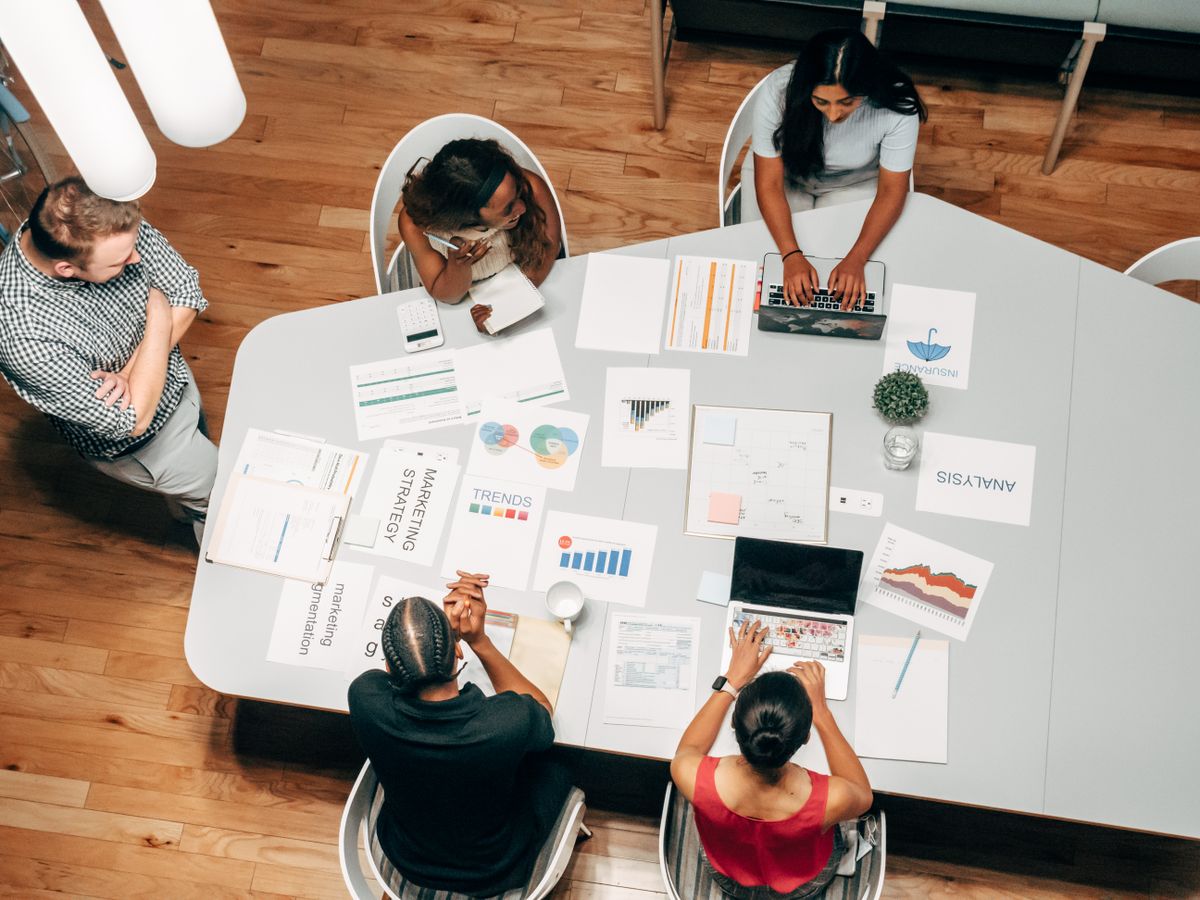 Kolleginnen und Kollegen einer Agentur diskutieren eine Medienstrategie am Tisch