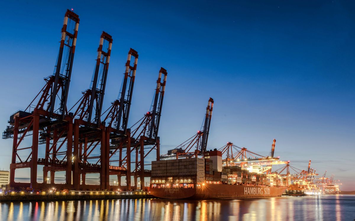 Verladekräne heben Container über einem Frachtschiff im Hafenbecken