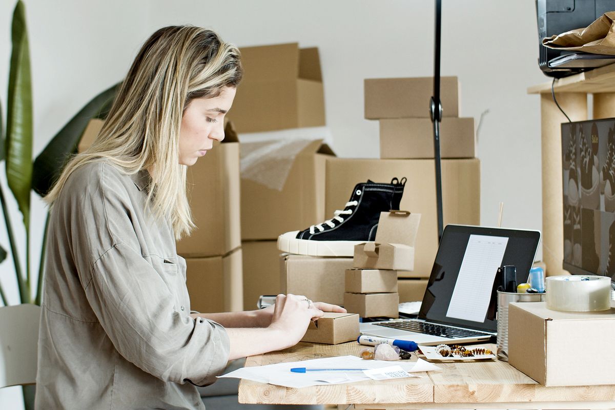 Shop-Betreiberin verpackt eine Bestellung aus ihrem Onlineshop in einen Versandkarton