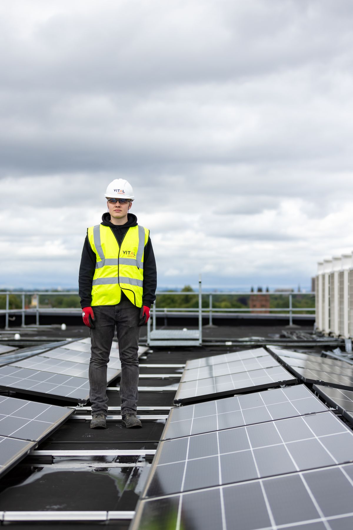 Solartechniker steht prüfend zwischen installierten Photovoltaik-Modulen auf einem Flachdach