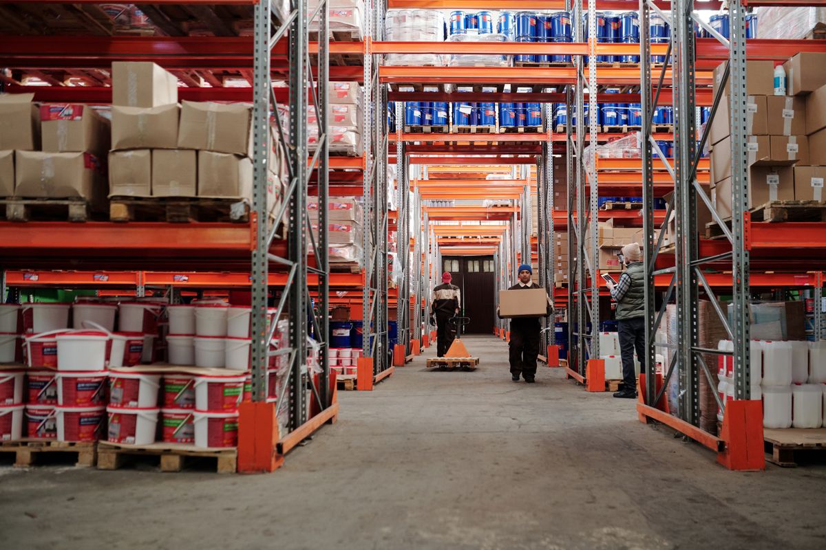 Mehrere Lagerarbeiter organisieren gemeinsam Kartons in einem Logistiklager