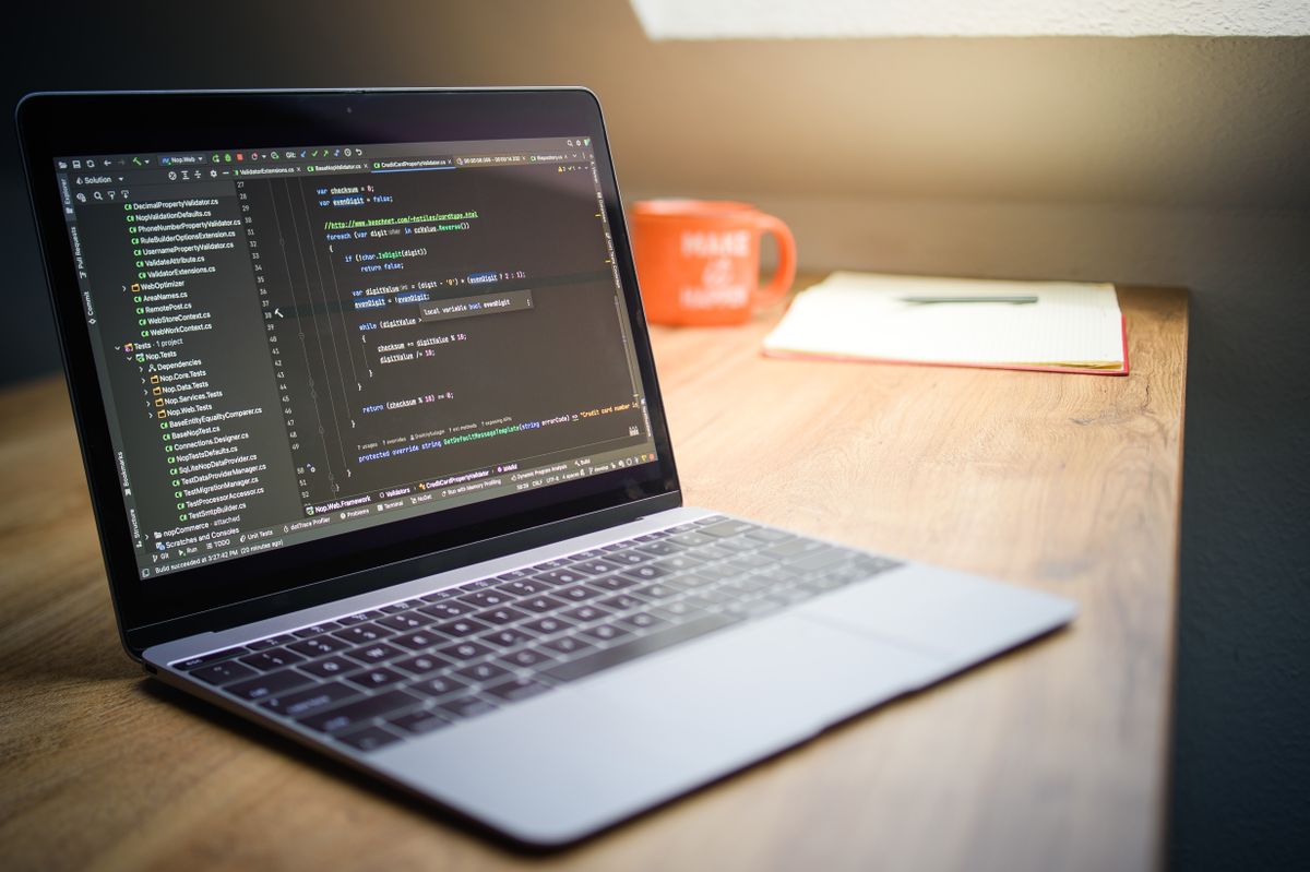 Moderner Laptop mit Quellcode auf einem Schreibtisch in einem Startup-Büro